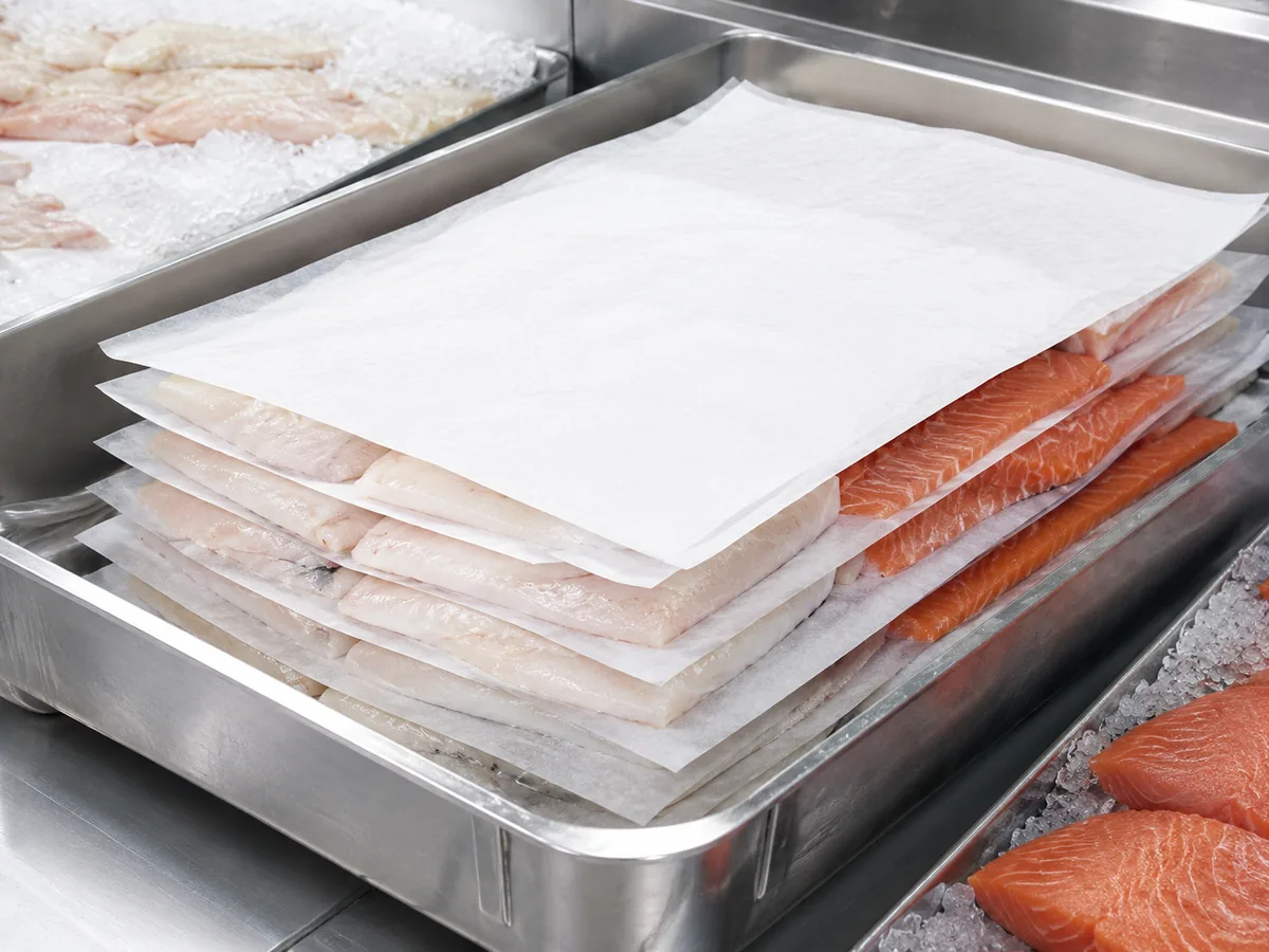 Pește și fructe de mare separate cu straturi intermediare din hârtie antiaderentă în procesarea refrigerată